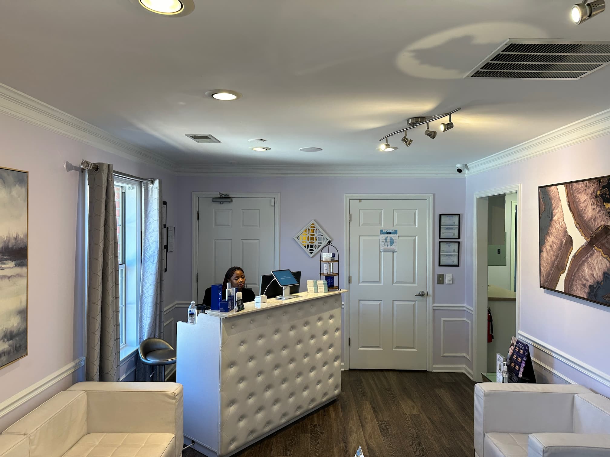 a woman sitting at a reception desk in a white room